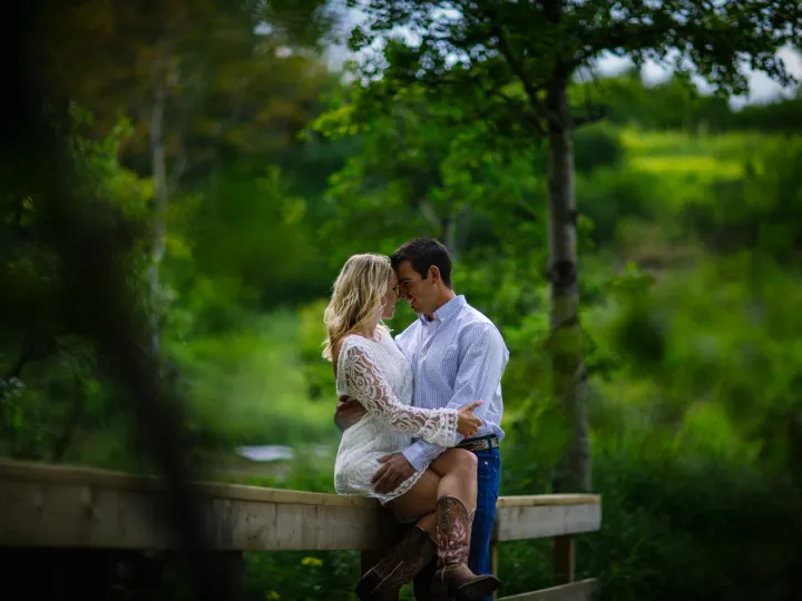 Couple sitting close on a bench near a waterfall during an engagement session