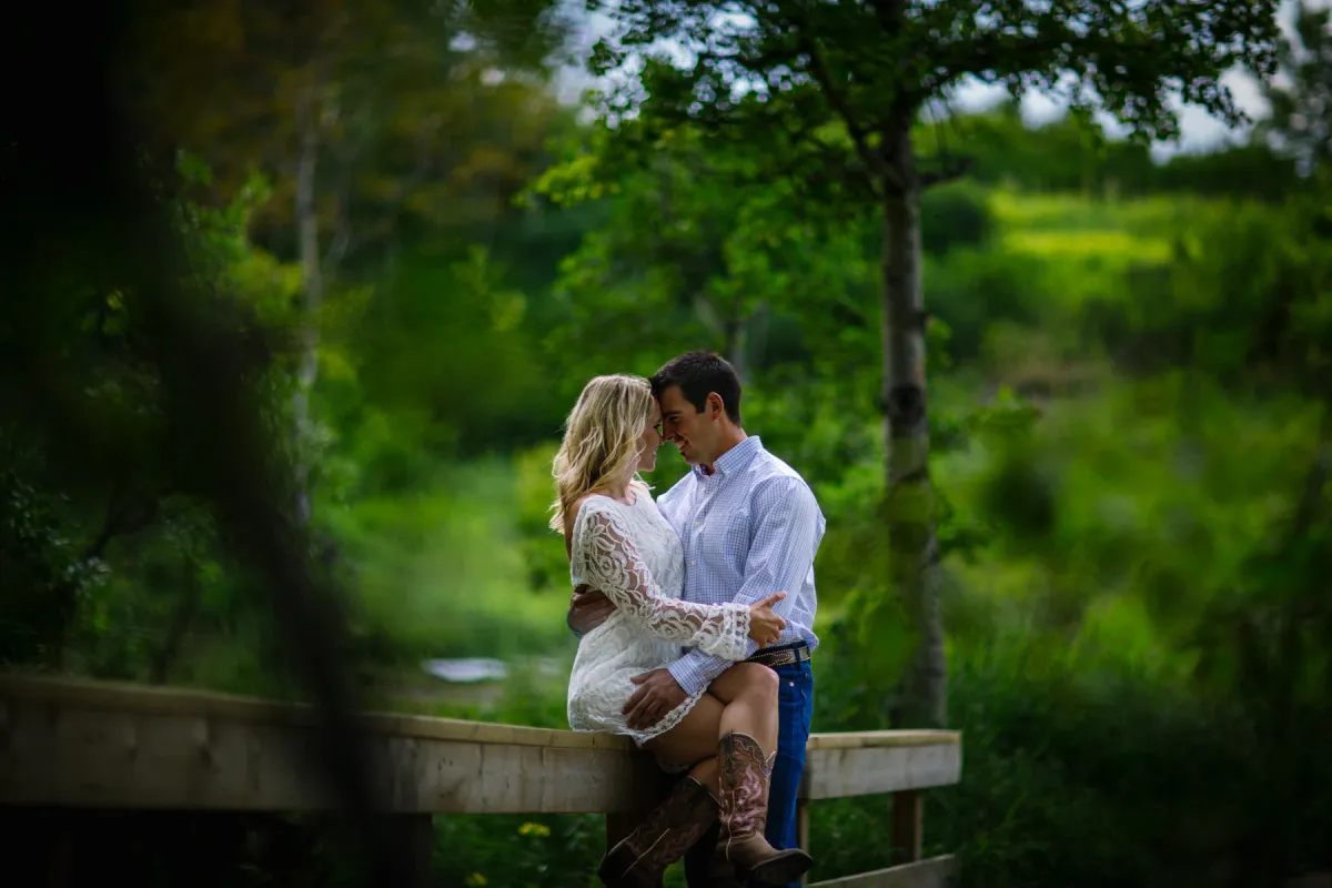 Couple sitting close on a bench near a waterfall during an engagement session