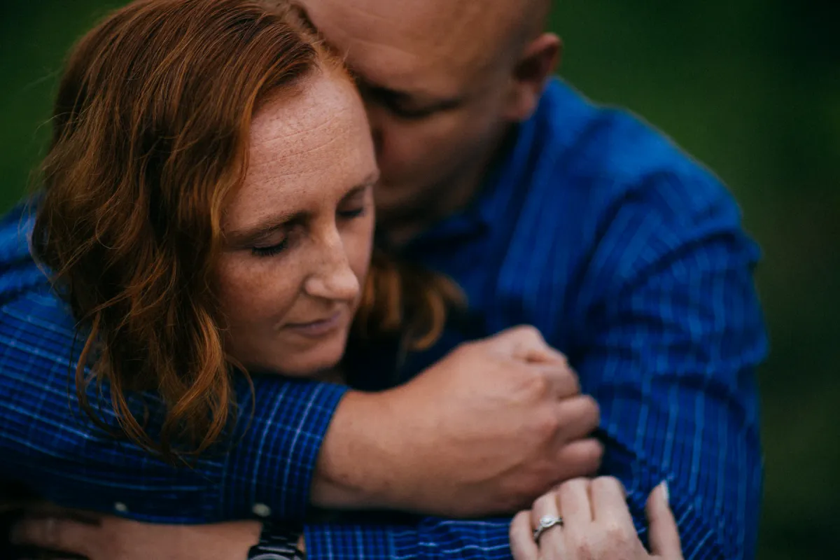 Couple holding each other closely in blue flannel during an engagement portrait