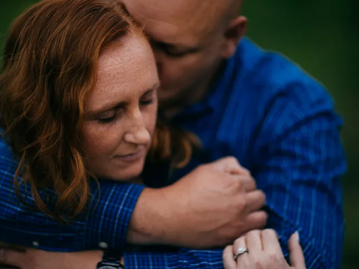 Couple holding each other closely in blue flannel during an engagement portrait