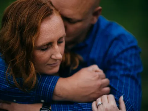 Couple holding each other closely in blue flannel during an engagement portrait