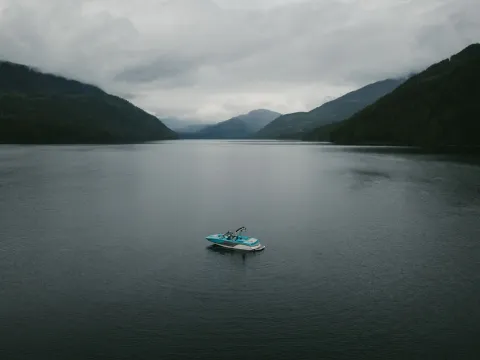 Small boat floating alone in the middle of a dark lake