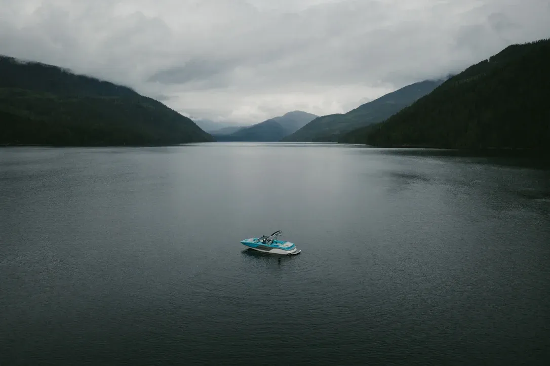 Small boat floating alone in the middle of a dark lake
