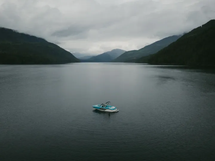 Small boat floating alone in the middle of a dark lake