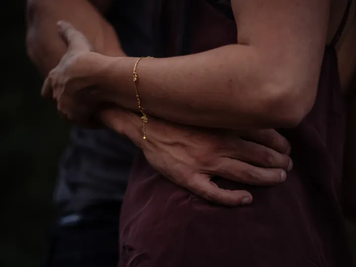 Close detail of a couple holding each other with a bracelet visible