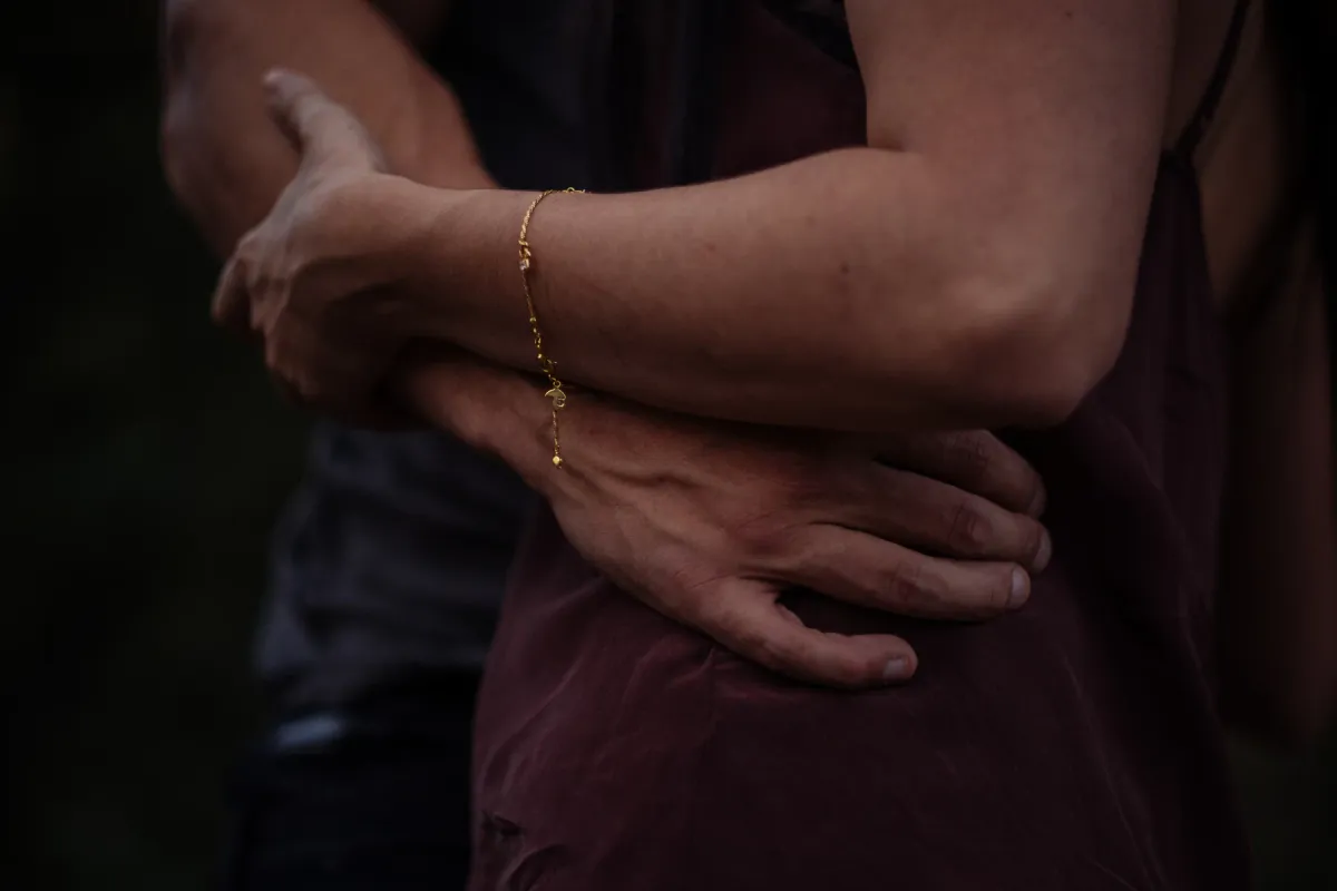 Close detail of a couple holding each other with a bracelet visible