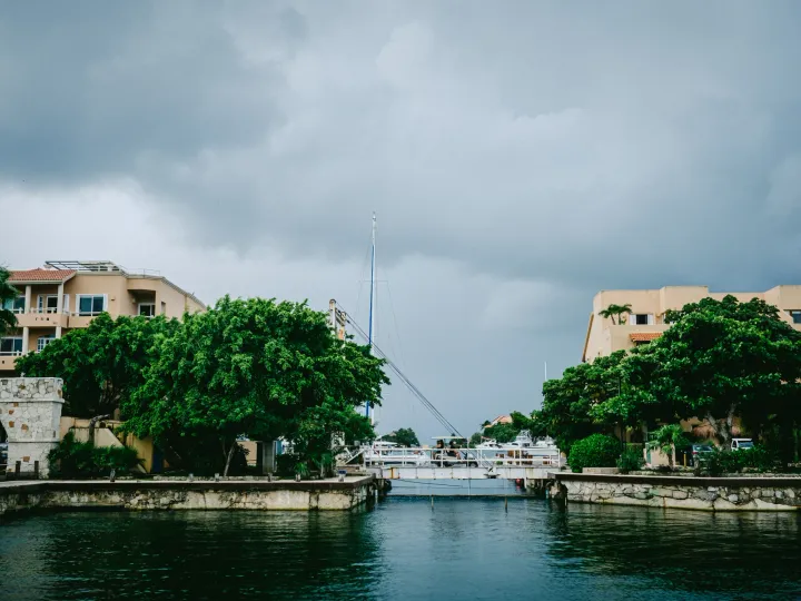 Canal lined with buildings and trees beneath gray rain clouds