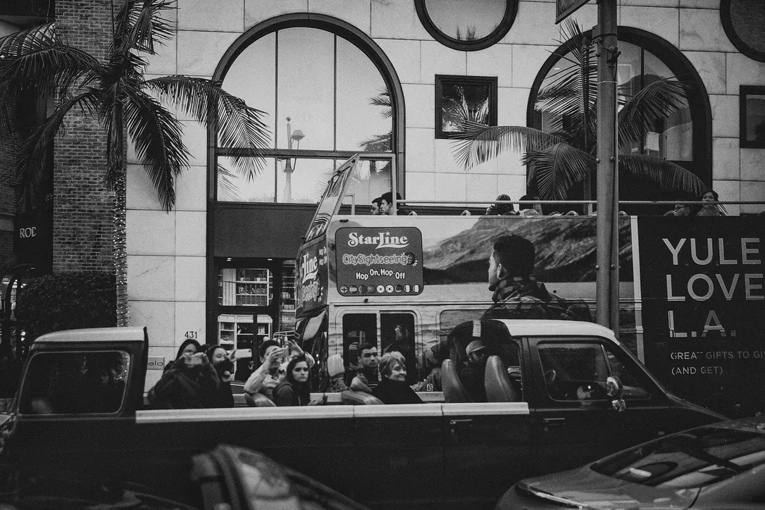 Black-and-white city scene with people visible through a bus window