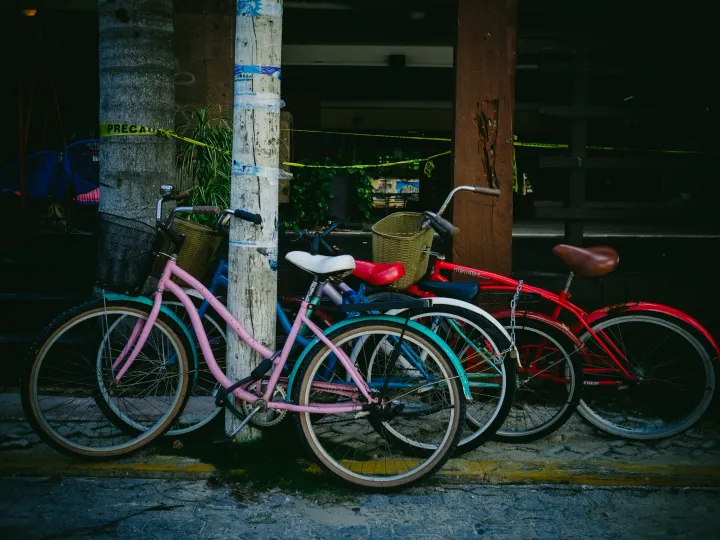 Row of pink and red bicycles parked in shade on a city street