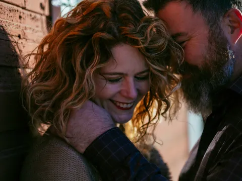 Couple laughing closely together during a candid engagement session