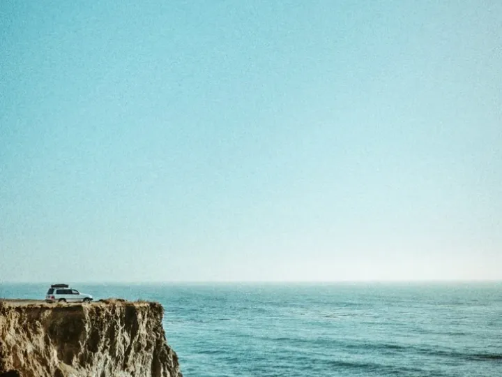 Steep coastal cliff above blue water