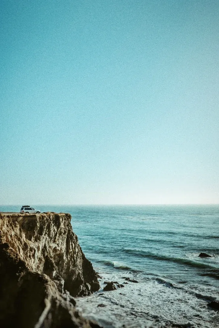 Steep coastal cliff above blue water