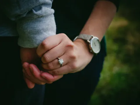 Close photo of a couple holding hands with an engagement ring visible