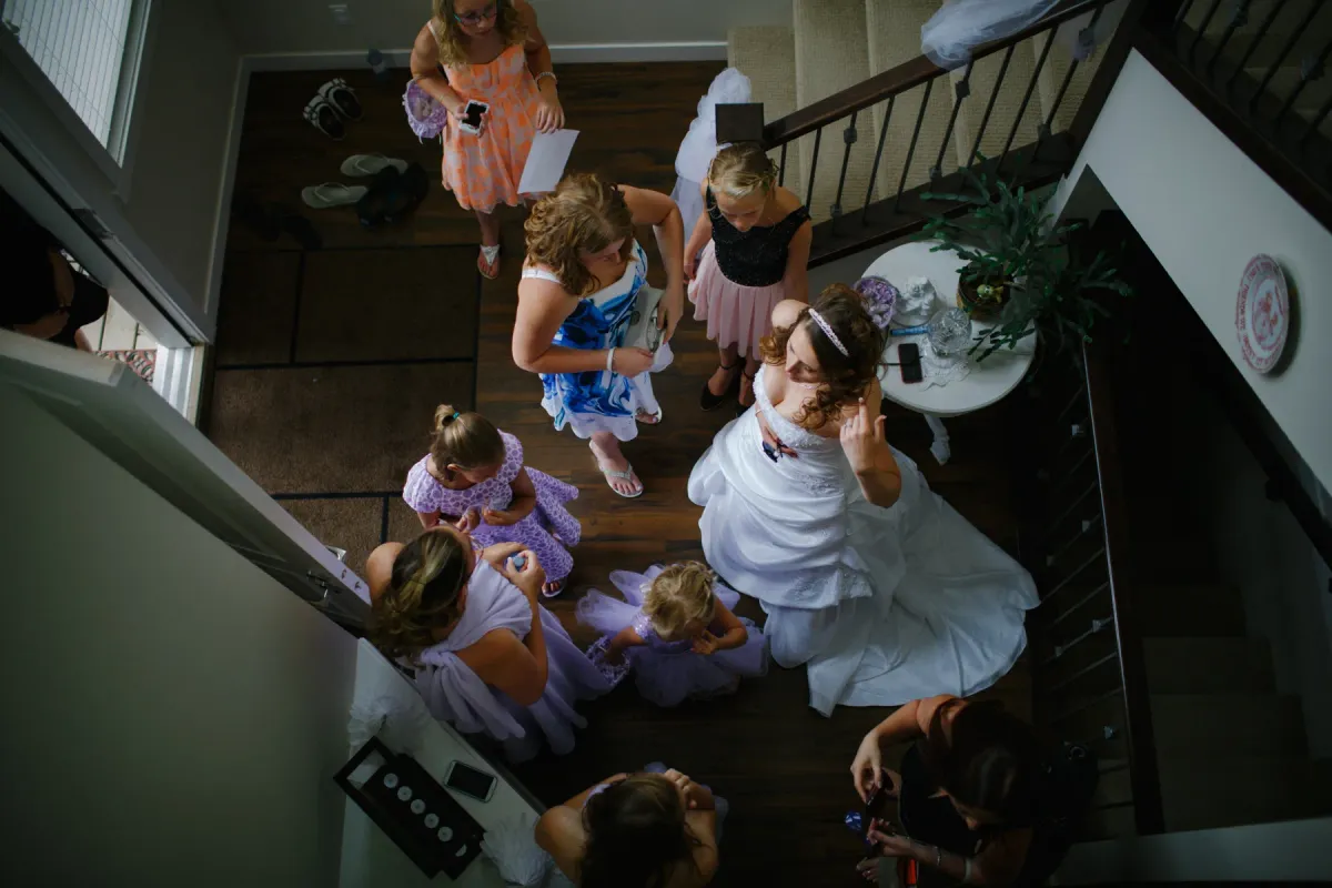 Overhead view of a bride in a ballgown surrounded by bridesmaids and flower girls in a foyer