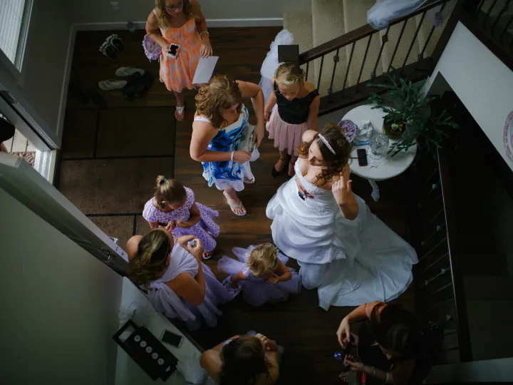 Overhead view of a bride in a ballgown surrounded by bridesmaids and flower girls in a foyer