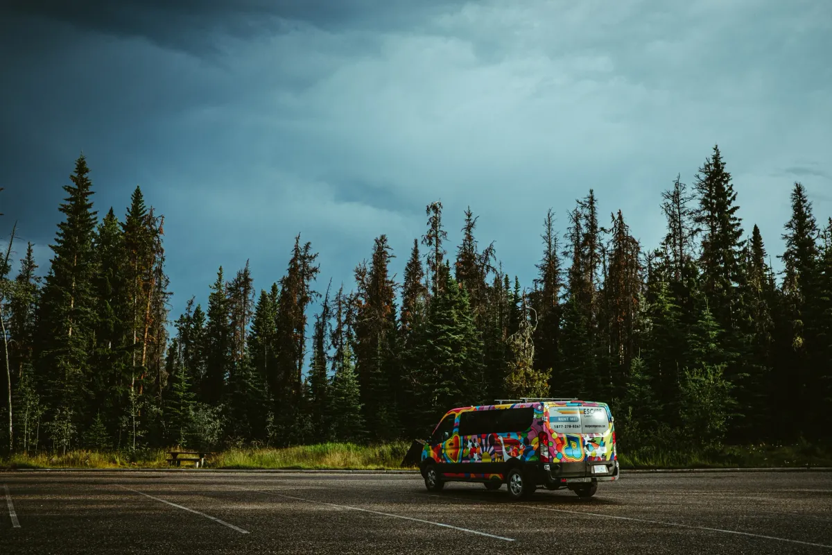 Bright party van with free hugs painted on it parked in an empty lot beneath storm clouds