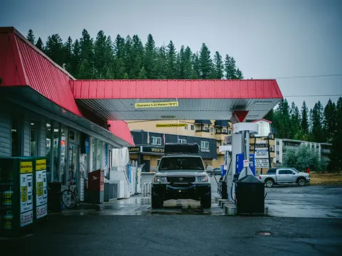 Small gas station with a red roof near dark trees