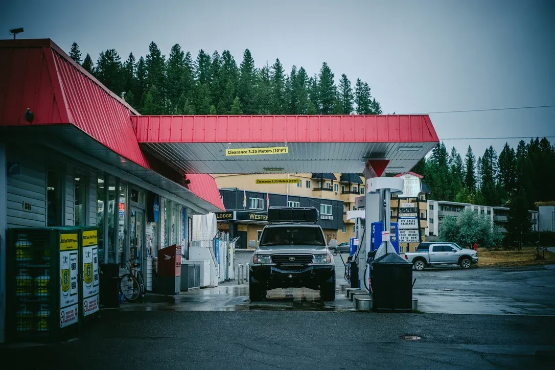 Small gas station with a red roof near dark trees