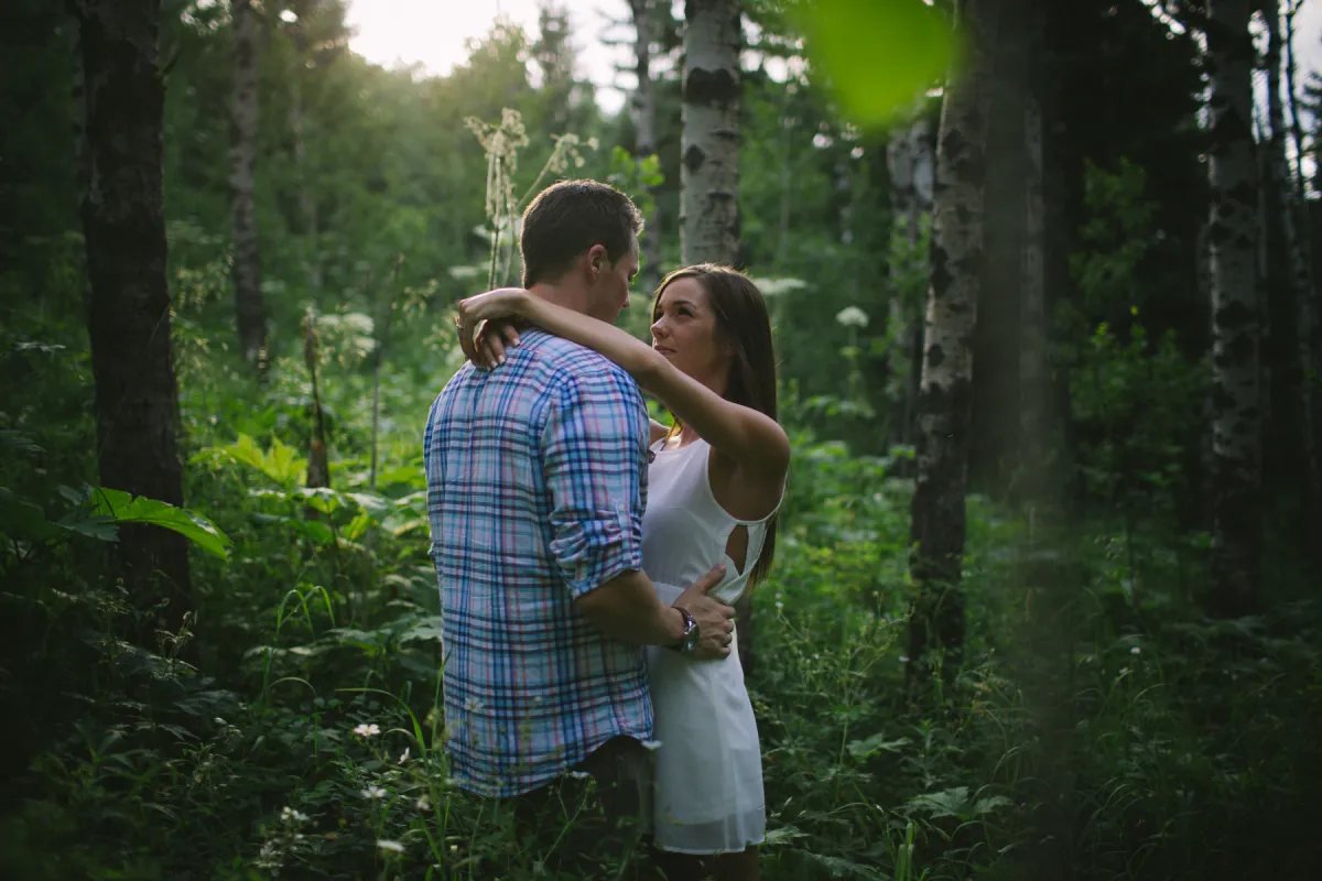 Couple holding each other in green woods during an engagement session
