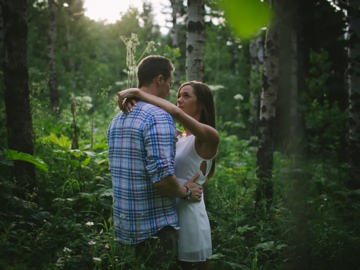 Couple holding each other in green woods during an engagement session