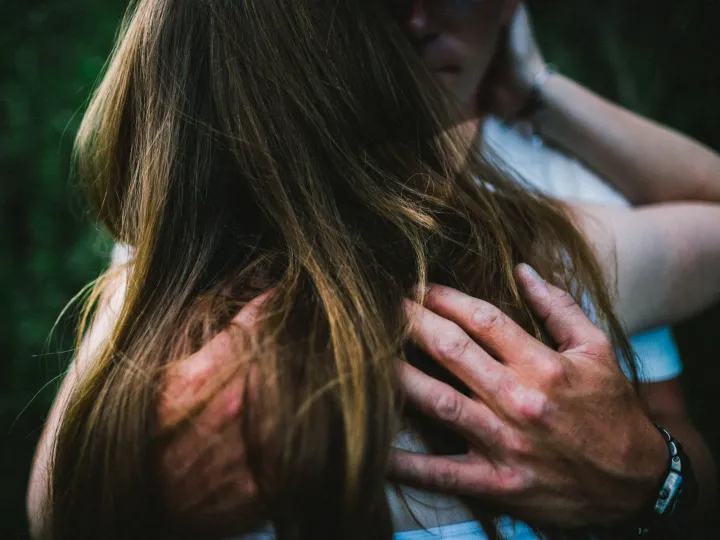 Close photo of hands resting behind a partner neck during an engagement session