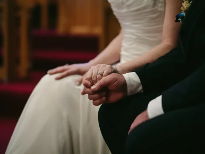 Close-up of bride and groom holding hands during a church wedding ceremony