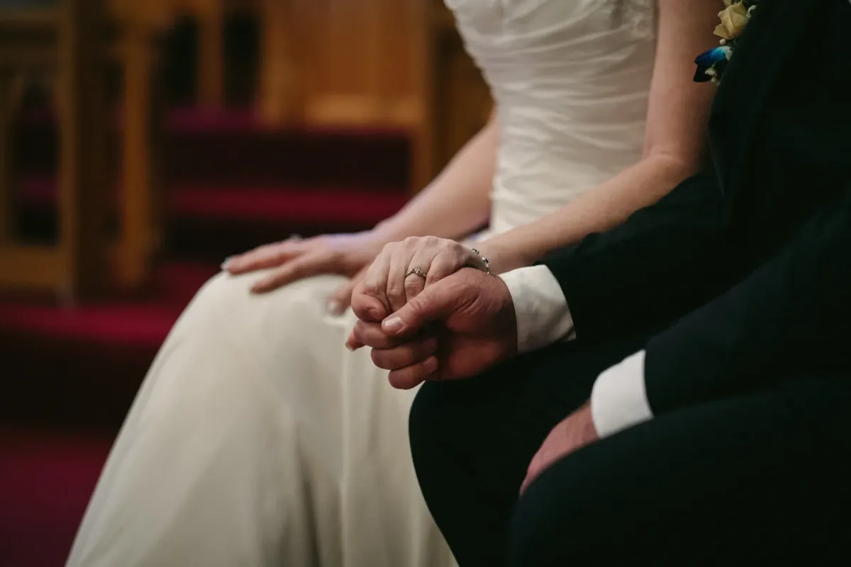 Close-up of bride and groom holding hands during a church wedding ceremony
