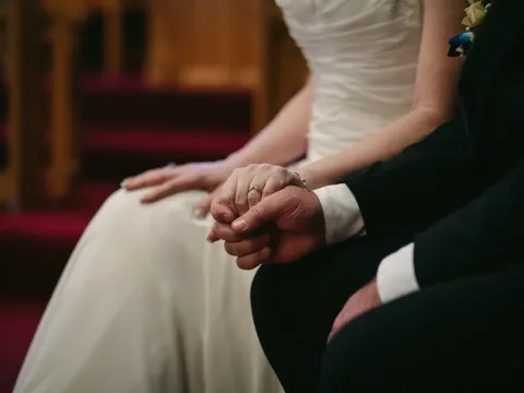 Close-up of bride and groom holding hands during a church wedding ceremony