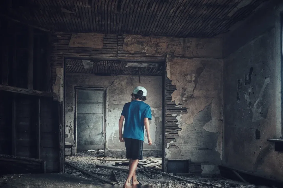 Person walking through a weathered room with damaged walls and soft light