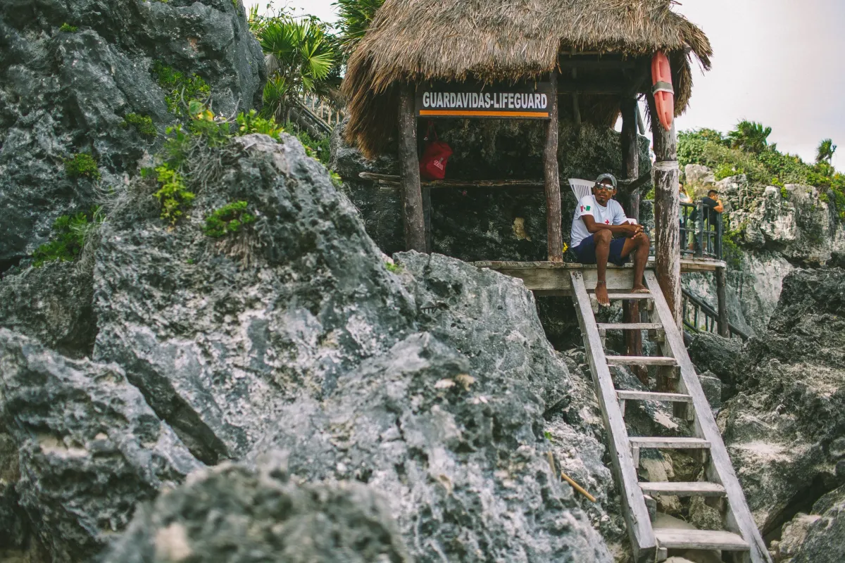 Small hut perched on rocky cliffs above bright coastal water