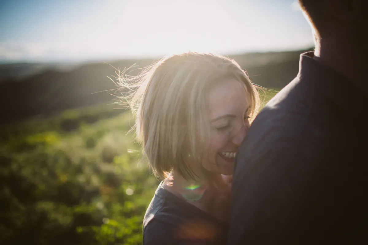 Couple laughing together in bright summer light during an engagement session