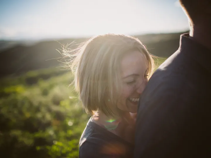 Couple laughing together in bright summer light during an engagement session