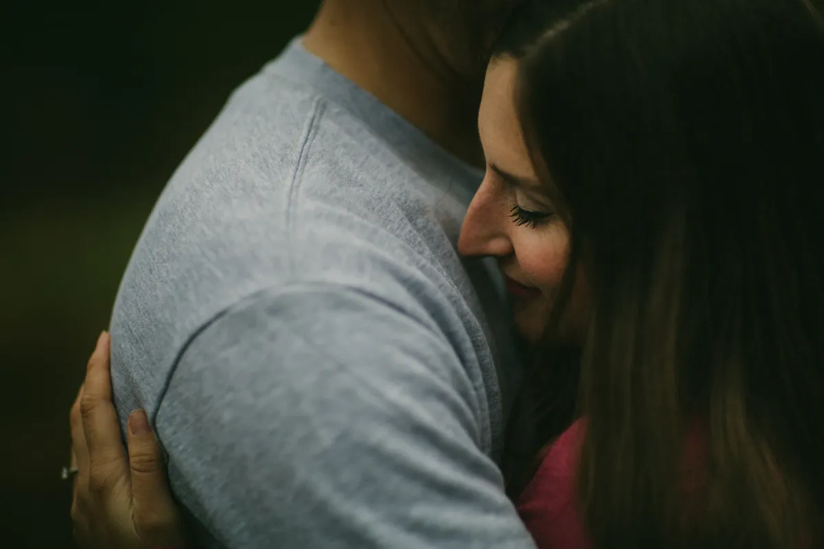 Woman laughing into her partner shoulder during a close engagement portrait