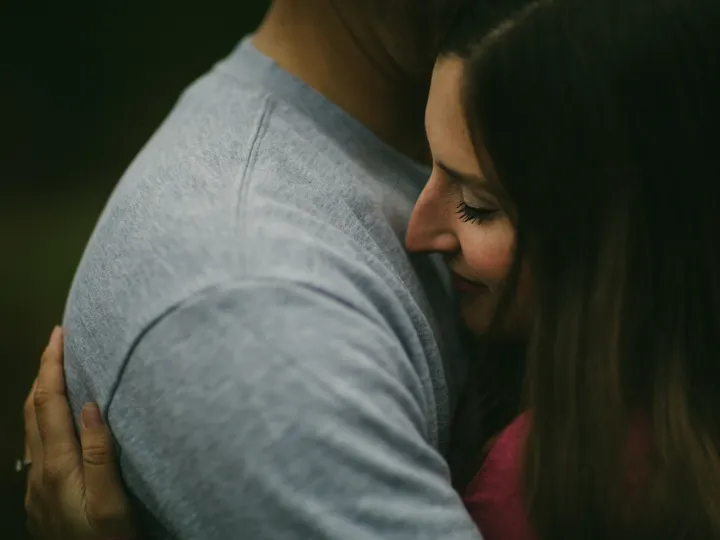 Woman laughing into her partner shoulder during a close engagement portrait