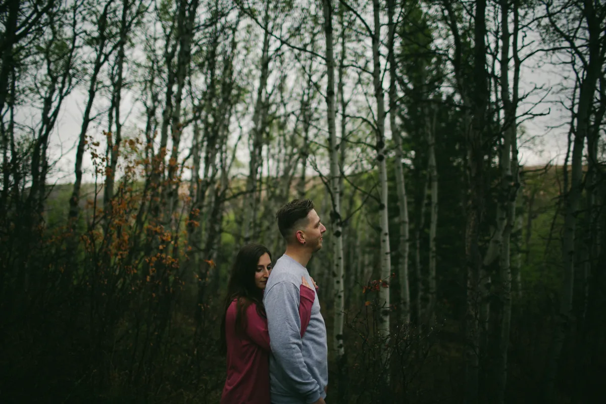 Couple standing among bare trees during an Alberta engagement session