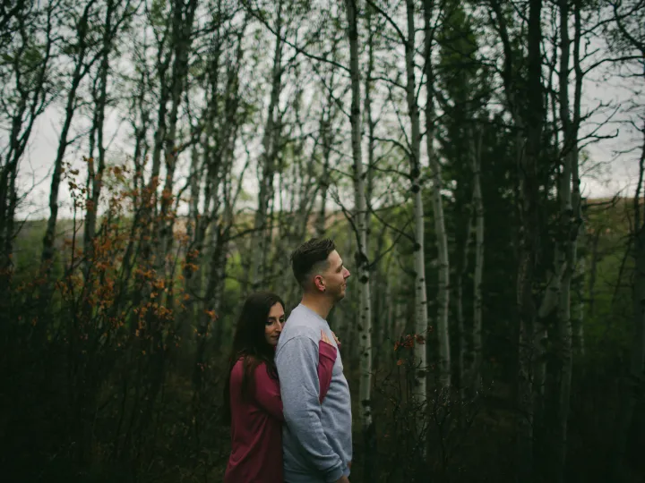 Couple standing among bare trees during an Alberta engagement session