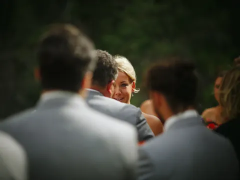 Candid close-up of a blonde bride's face framed by blurred guests during an outdoor ceremony