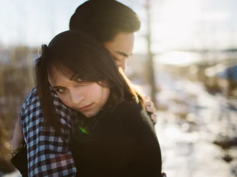 Woman looking toward the camera while leaning into her partner during a couples session