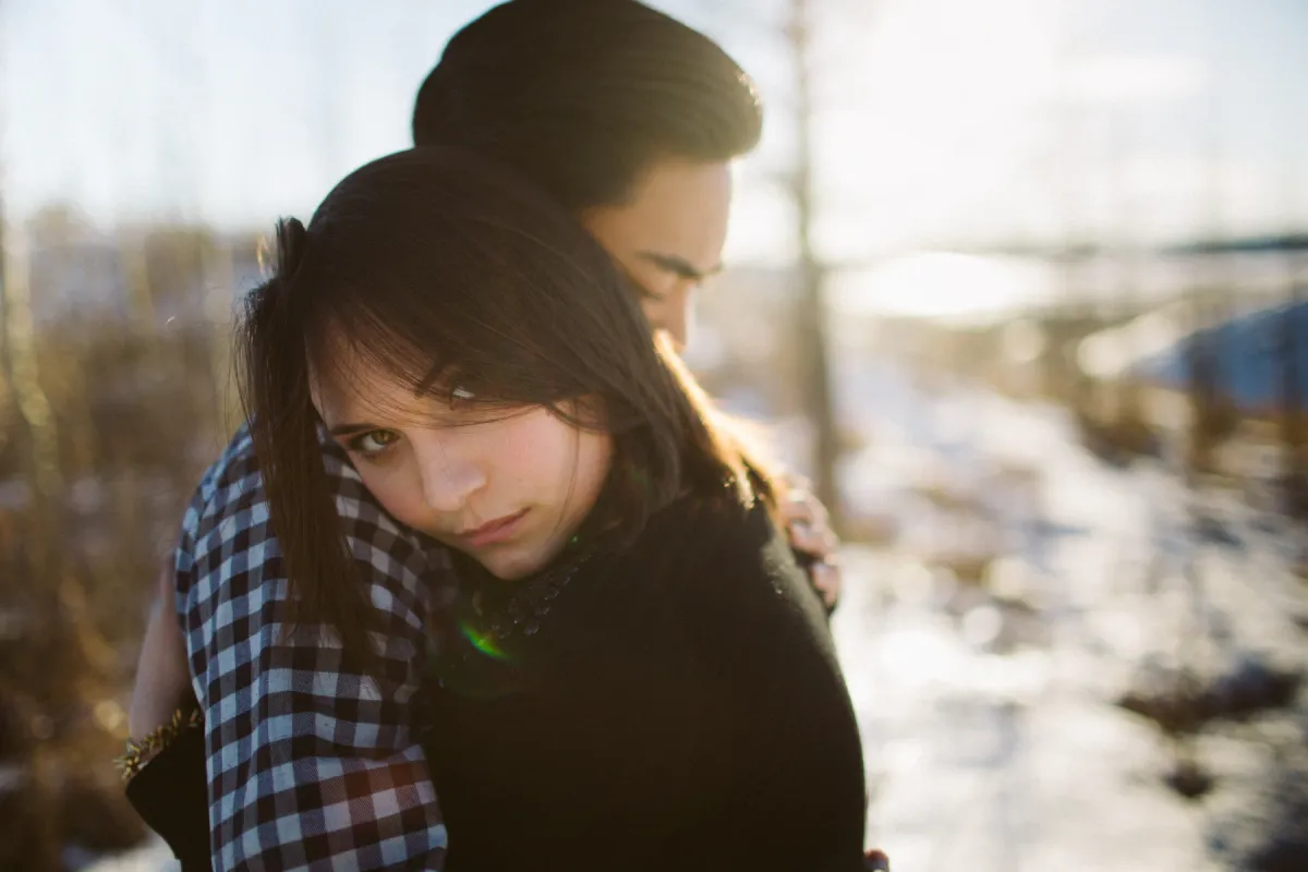 Woman looking toward the camera while leaning into her partner during a couples session