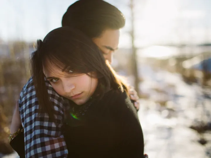 Woman looking toward the camera while leaning into her partner during a couples session