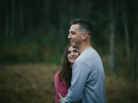 Couple standing close in woods during an engagement portrait