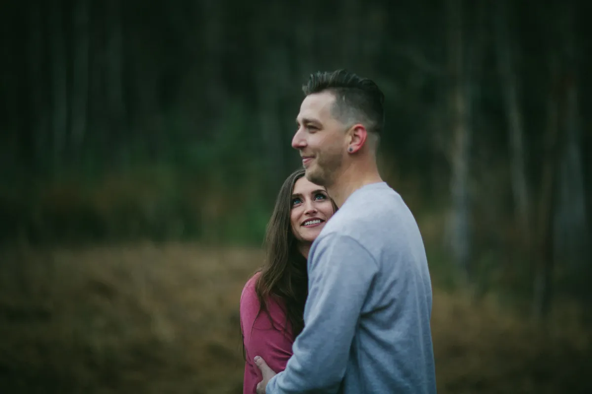 Couple standing close in woods during an engagement portrait