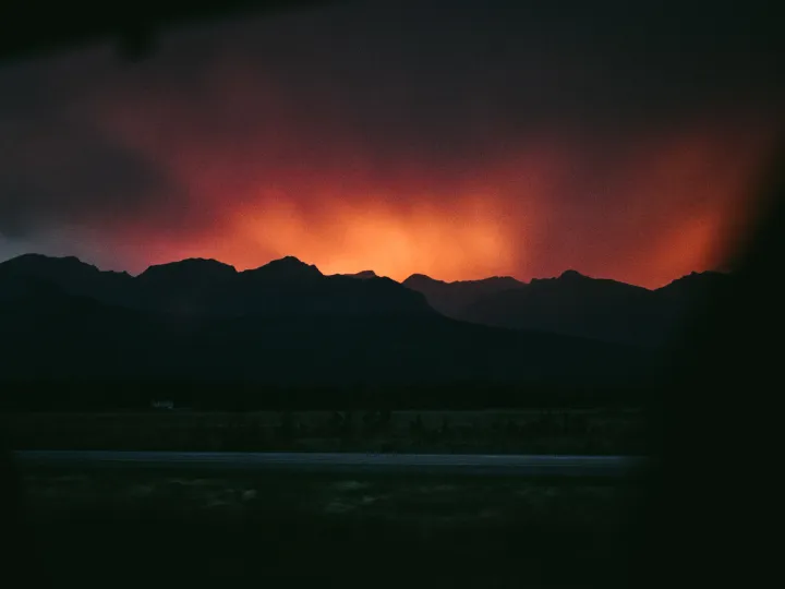 Deep red sunset light glowing behind dark mountain ridges