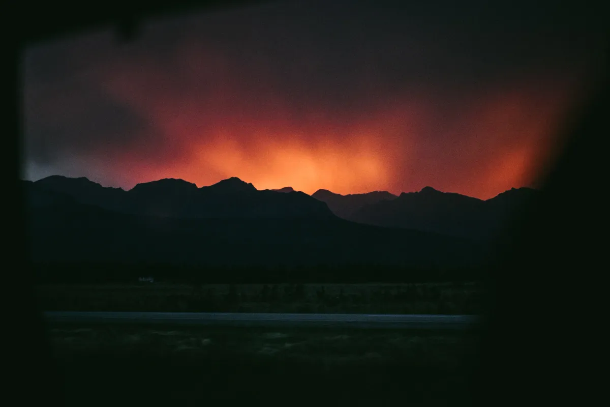 Deep red sunset light glowing behind dark mountain ridges