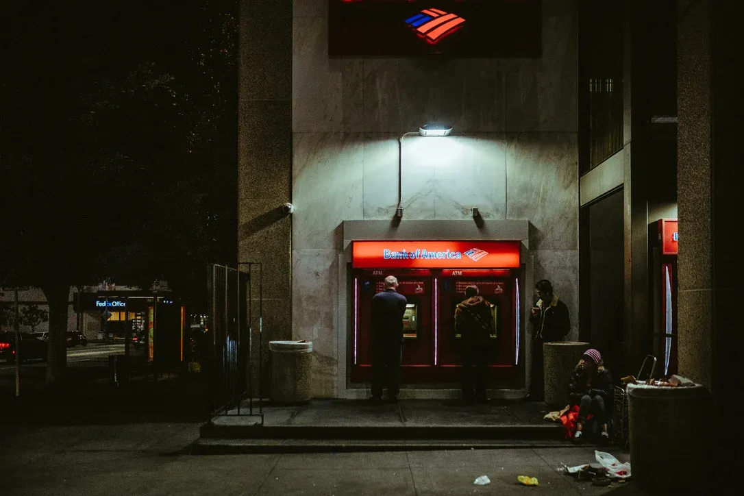 Lit ATM entrance glowing red on a dark street at night