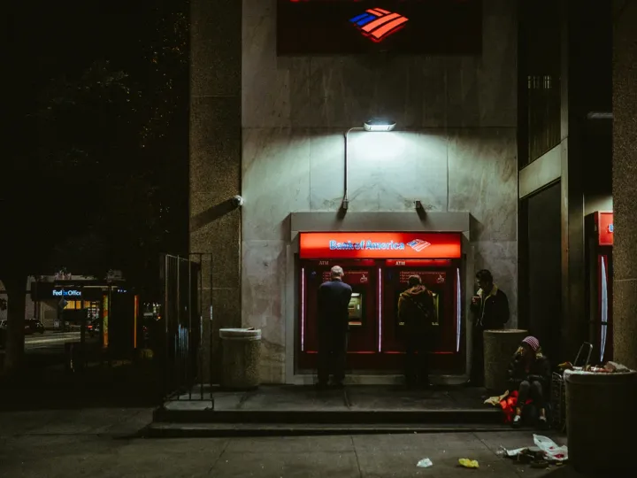 Lit ATM entrance glowing red on a dark street at night
