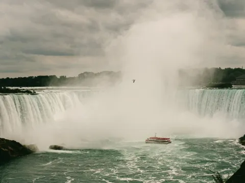 Niagara Falls spray rising over moving water and distant boats
