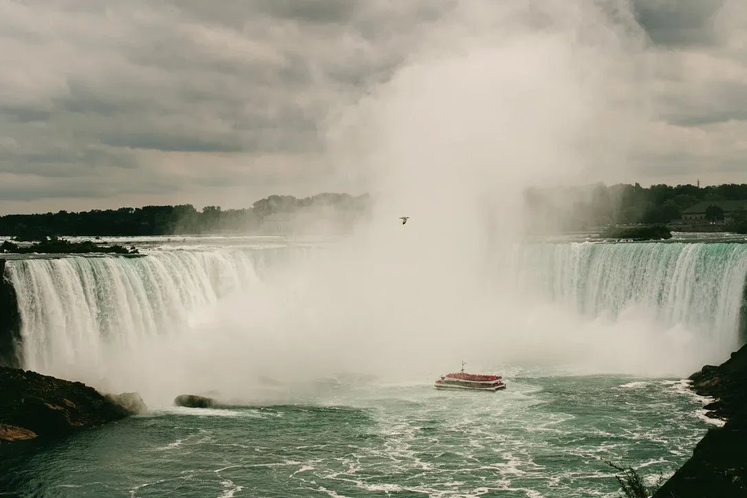 Niagara Falls spray rising over moving water and distant boats