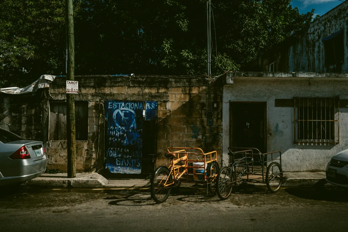 Bicycles parked near a blue doorway and weathered wall on a city street