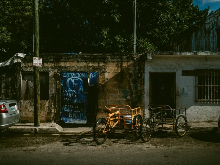 Bicycles parked near a blue doorway and weathered wall on a city street
